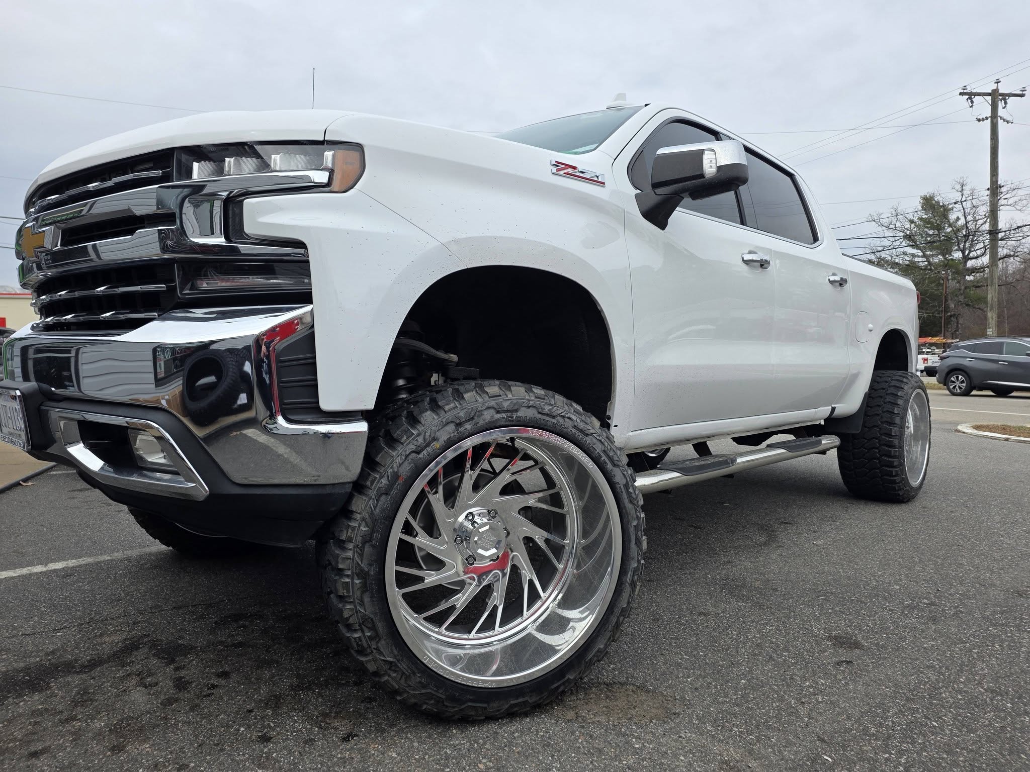 Lifted white Chevy truck with chrome wheels